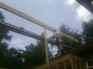 Carpenter setting a ridge beam over a new addition frame — Ice Dam Removal by Roofing Brothers in Stittville