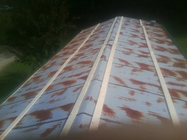 Rusted metal roof panels with new wood purlins before replacement — Storm Damage Roof Repair in Stittville by Roofing Brothers