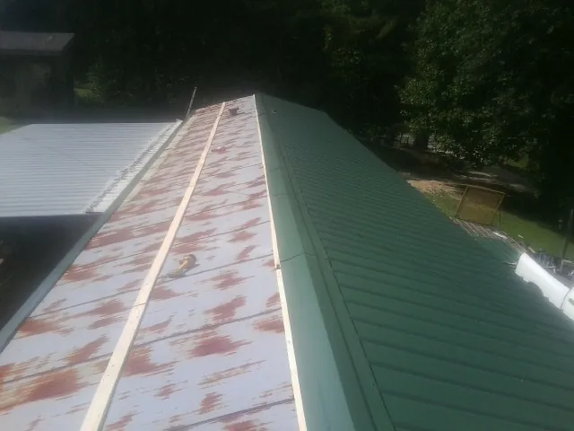 Old rusted panels beside newly installed green metal roofing — Wind Damage Roof Repair by Roofing Brothers in Stittville