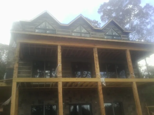 Dormers and porch framing on a large log home under construction — Roof Coating work by our crew in Stittville