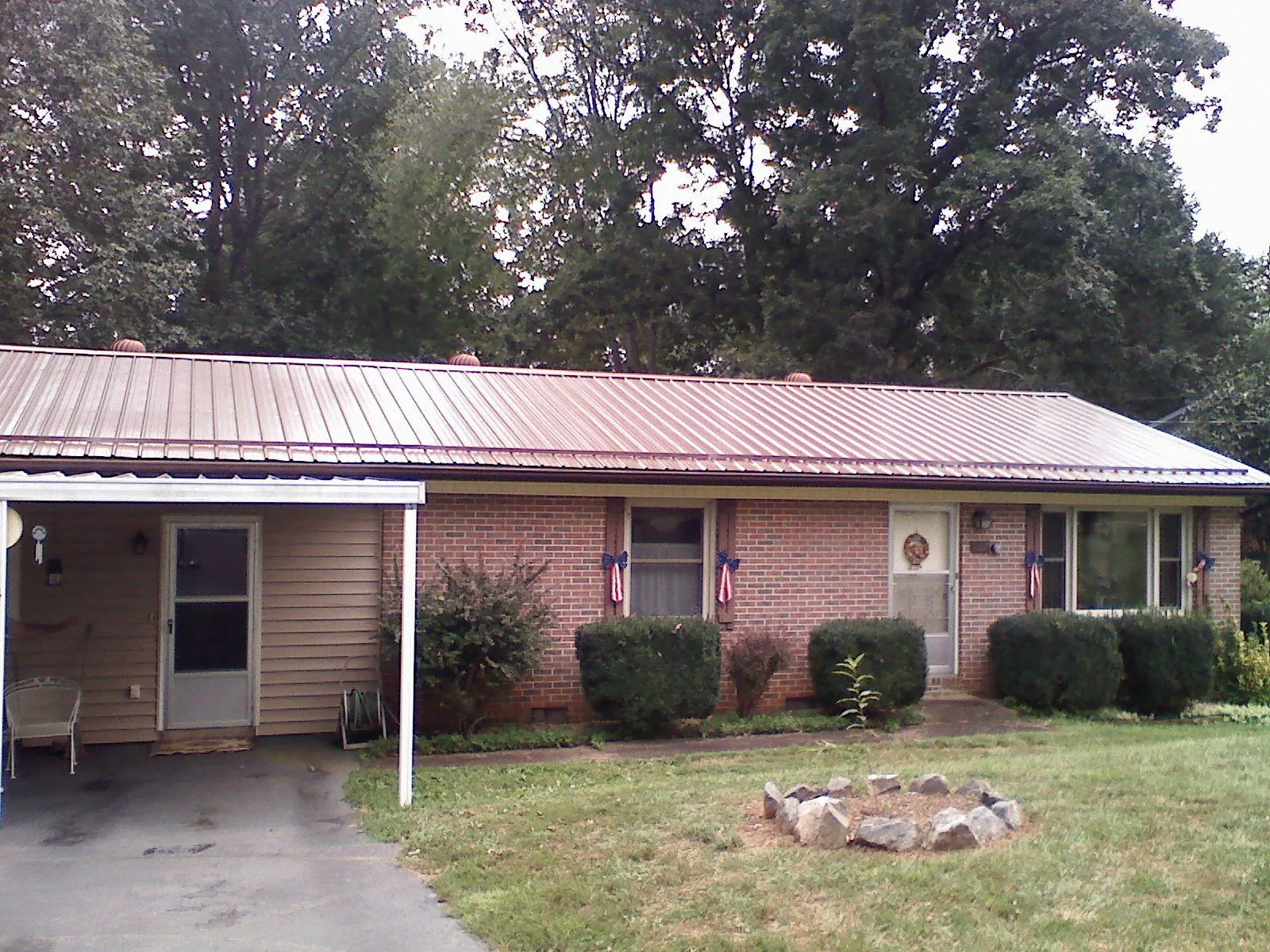 Bronze metal roof and carport on a brick ranch home — Roof Repair work by our crew in Stittville