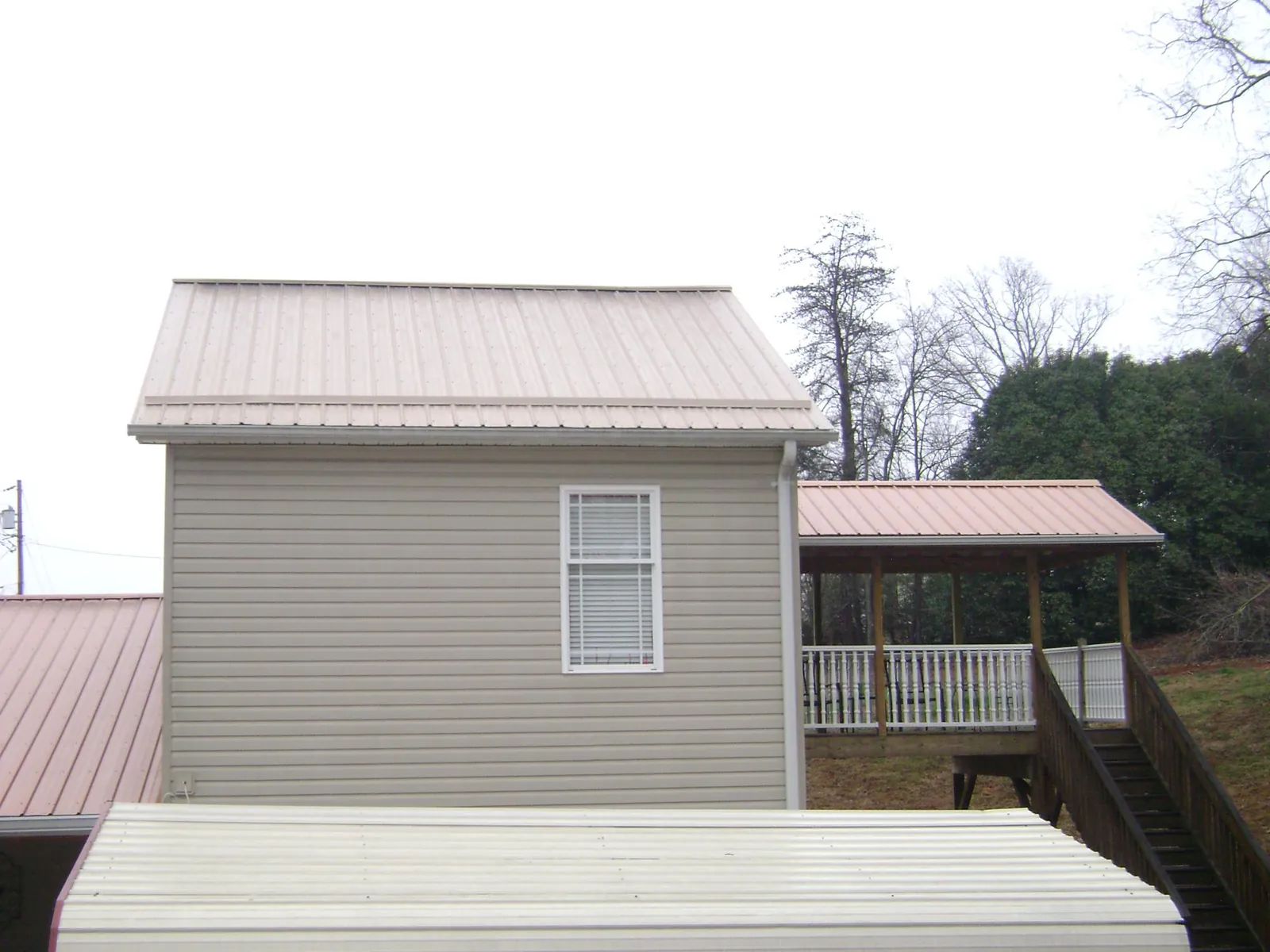 Tan metal roofs on a two story addition and attached porch, from a Roof Replacement job in Stittville