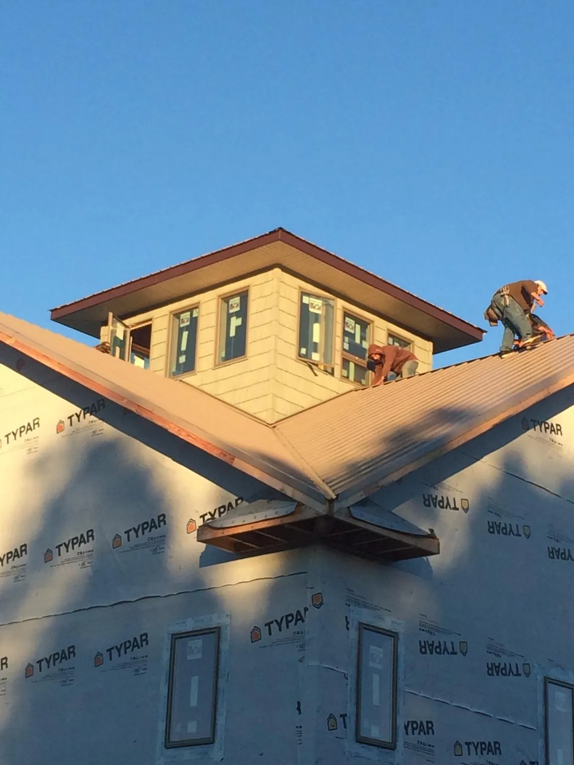 Roofers working around a rooftop cupola on a new metal roof at sunset — Roof Waterproofing in Stittville by Roofing Brothers